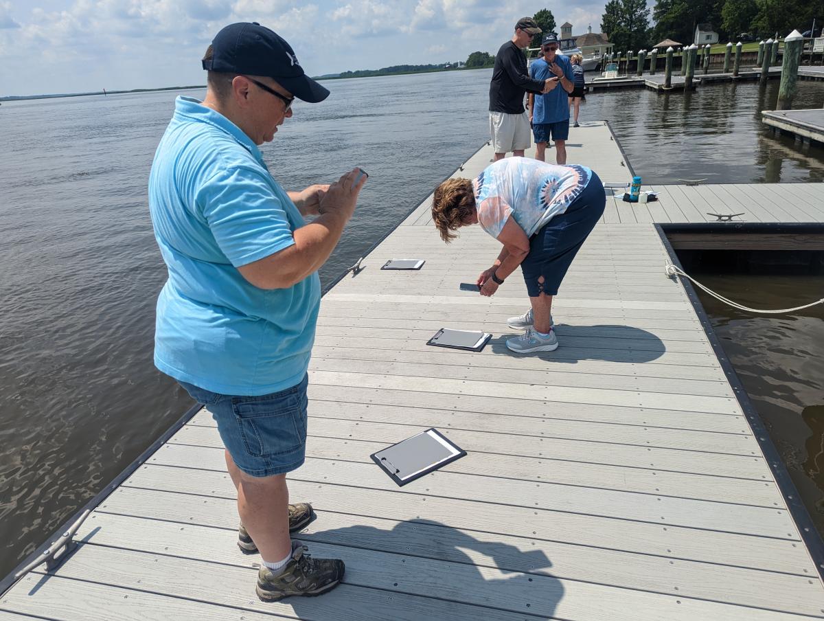 Group of volunteers learning how to use HydroColor app on their phones out on a dock.