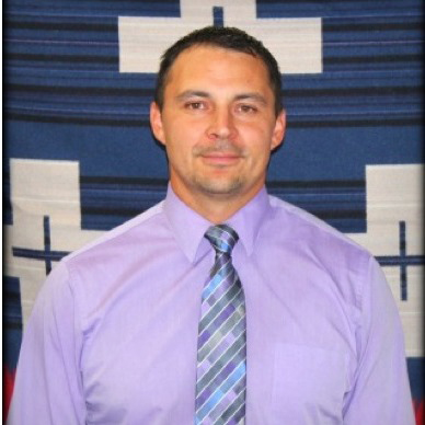 Head and shoulders picture of Cody Desautel, wearing a purple shirt and a tie with blue, purple and silver stripes