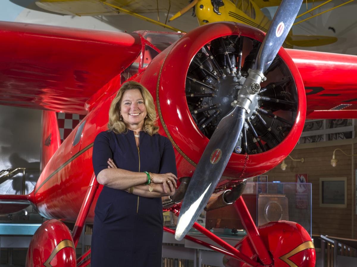 Ellen Stofan smiling beside a red plane in a museum hangar