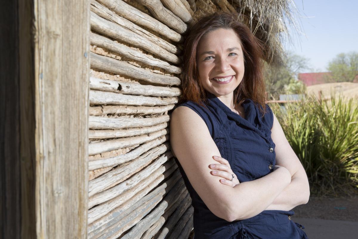 Katharine Hayhoe outside, leaning against a wooden wall