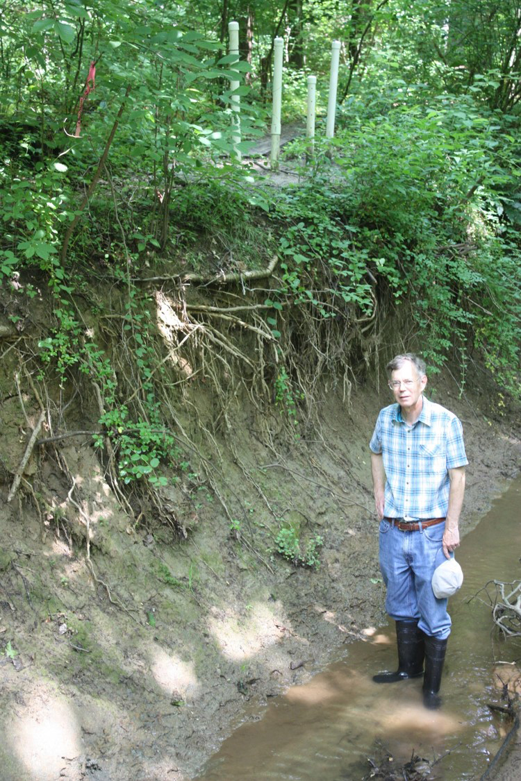 Scientist standing in a deep streambed