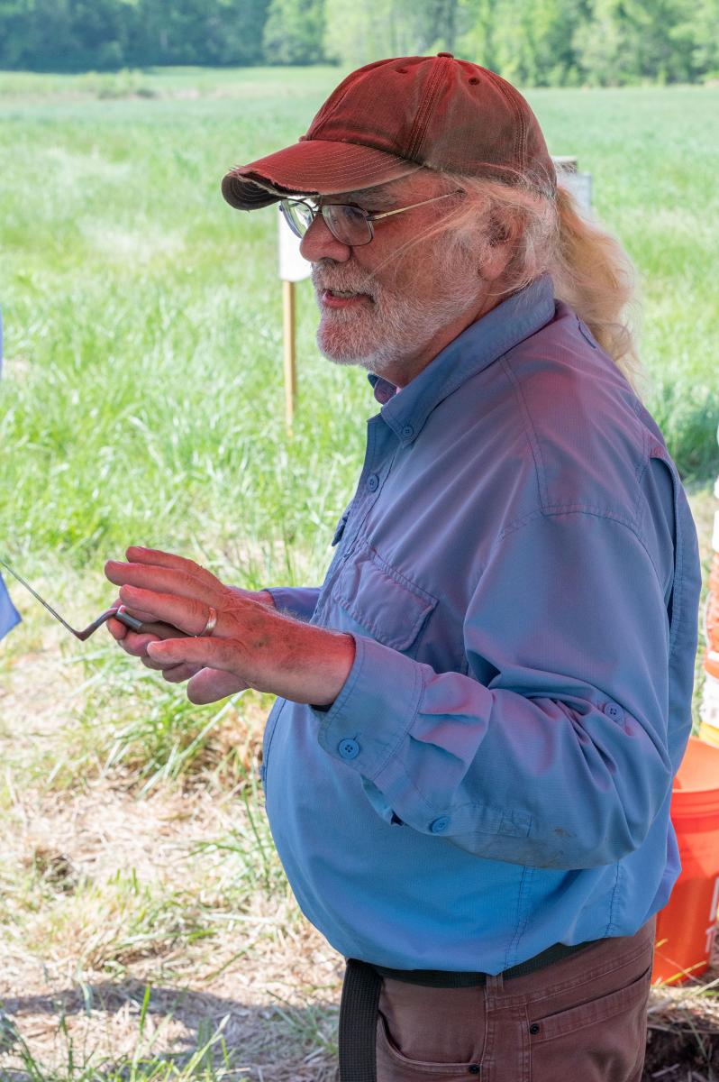 Man with long white hair in a ponytail, wearing glasses and a red cap