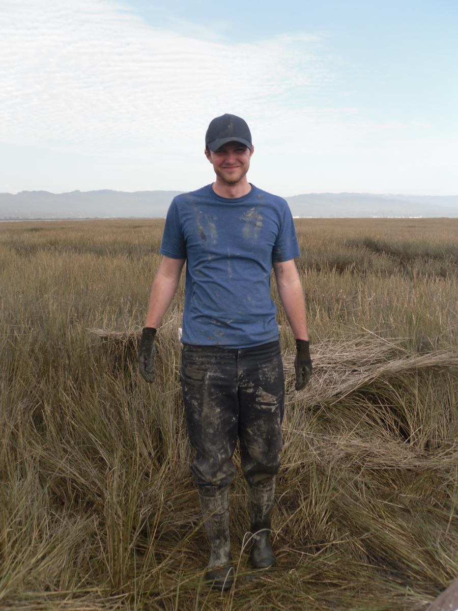 Man standing in wetland in muddy clothes