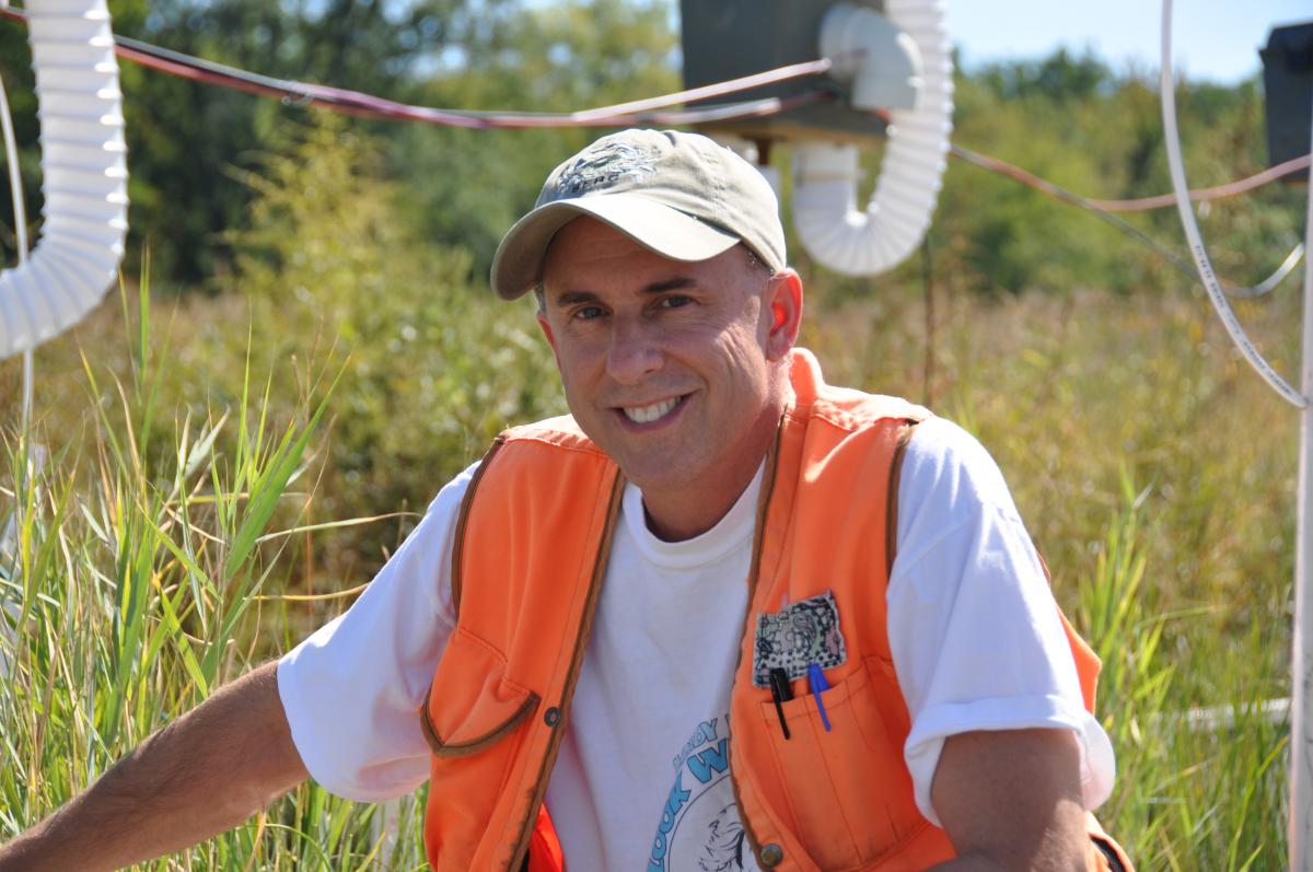 Man in orange vest sitting in a marsh