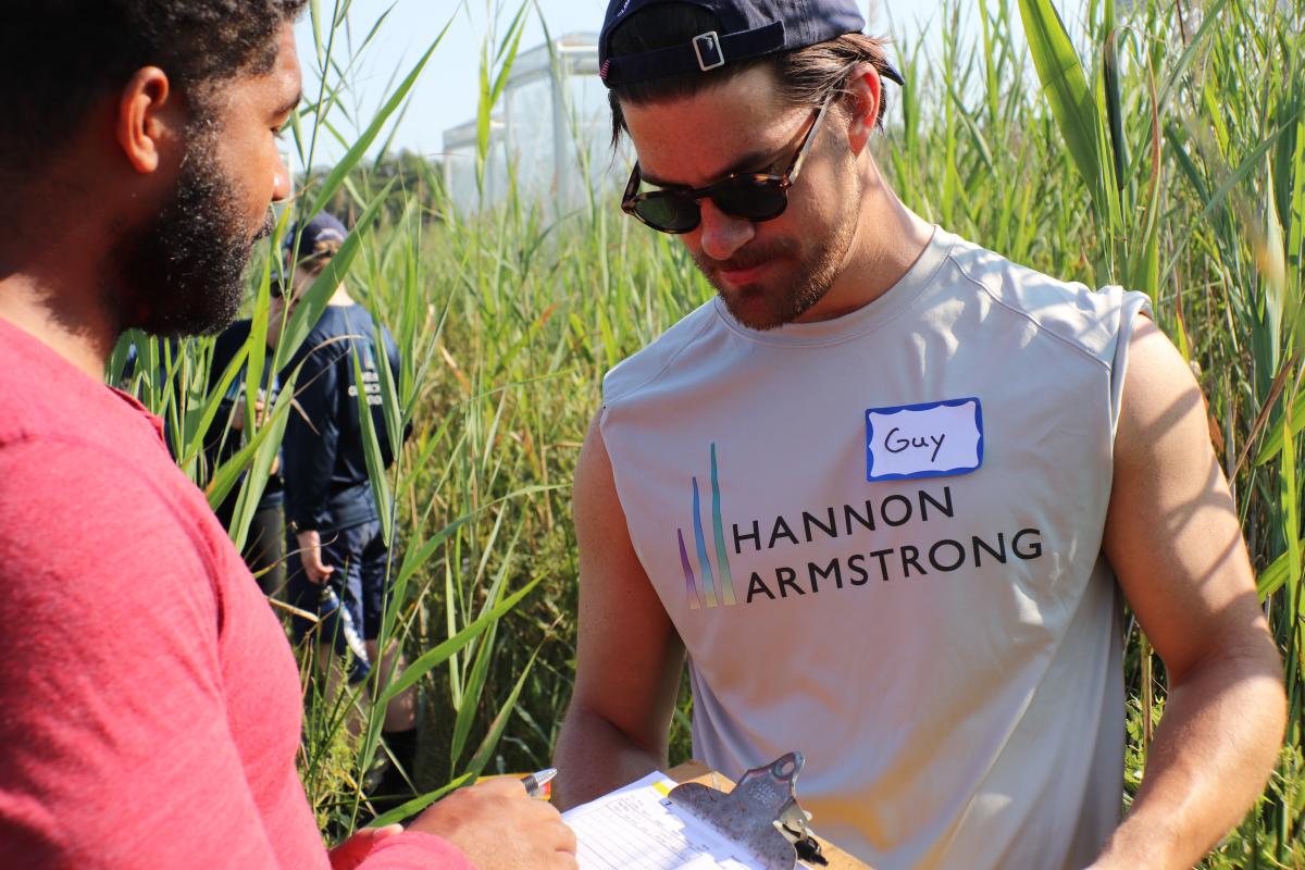 Man in Hannon Armstrong T-shirt looks at clipboard with SERC scientist