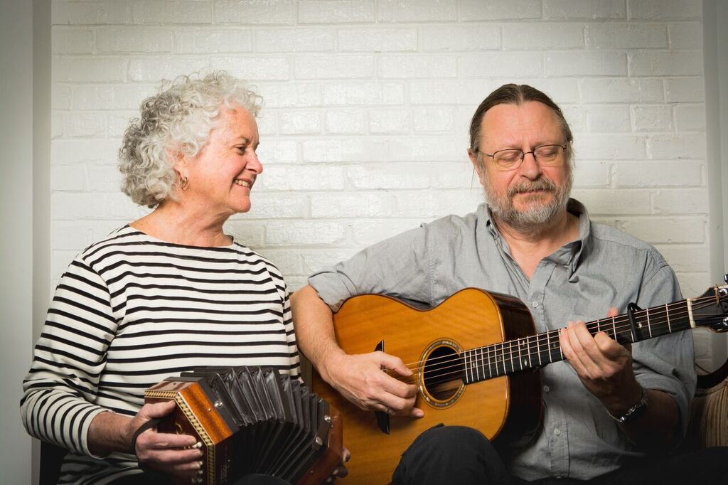 A woman playing accordion next to a man playing guitar