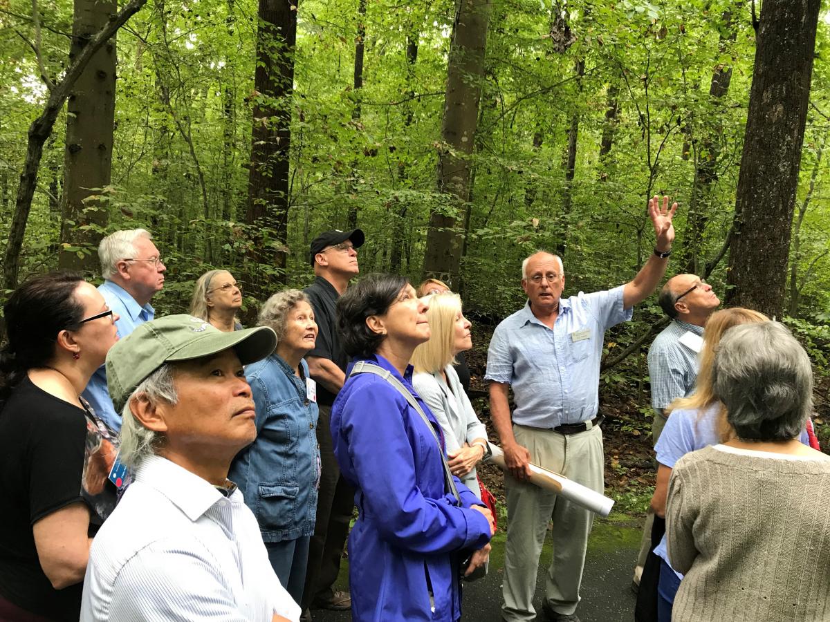 Scientist talking to group of visiting adults in a forest