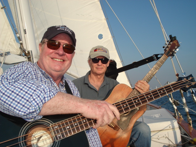 Two men on a boat with guitars