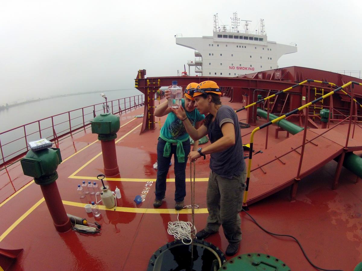 Two scientists inspect water sample on boat