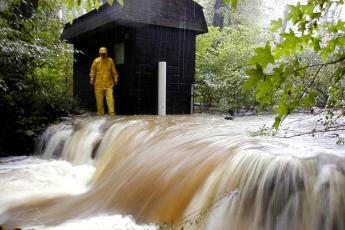 Scientist Tom Jordan by a SERC weir during a storm. There is a lot of water flowing from right to left