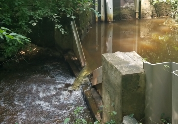 A stream flowing through a weir, or low-head dam. 