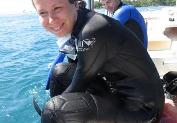 Sarah Gignoux-Wolfsohn, a young woman with dark hair, sits in a black wet suit on the edge of a boat