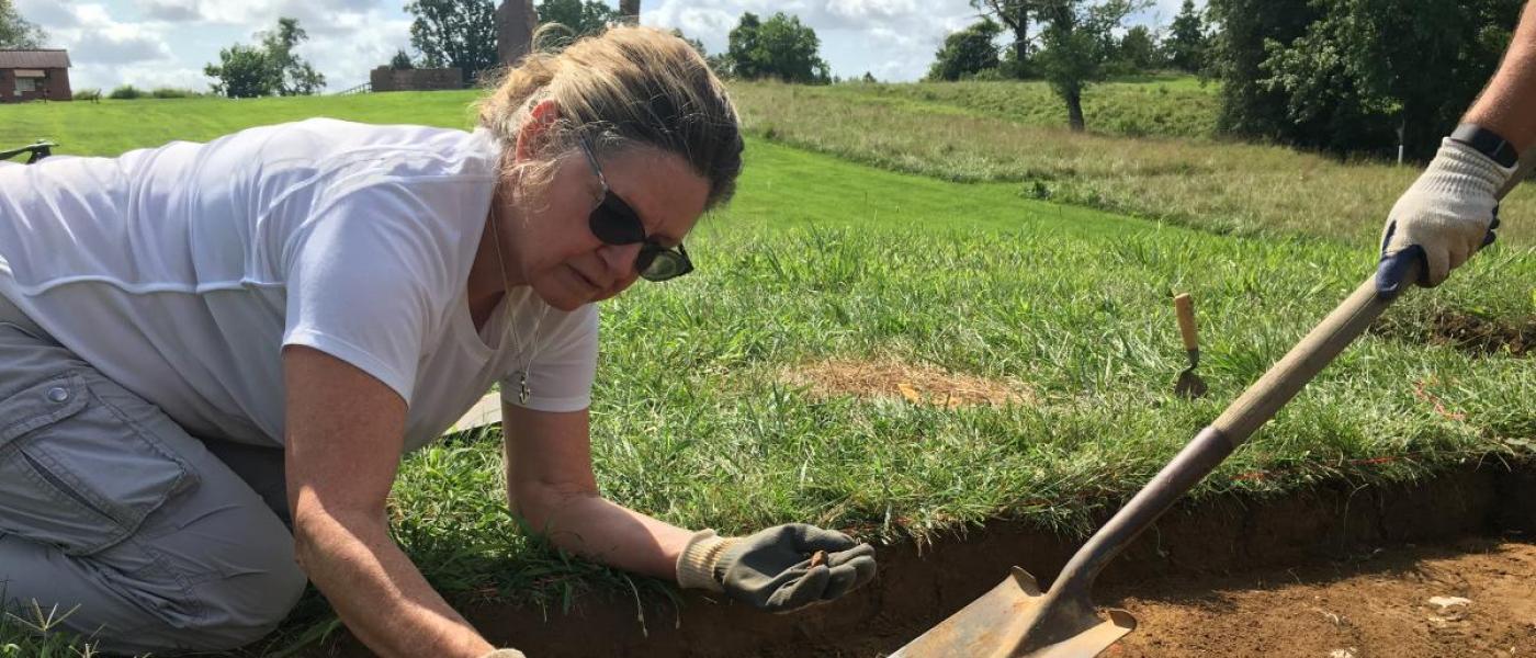 Woman digs in soil plot 