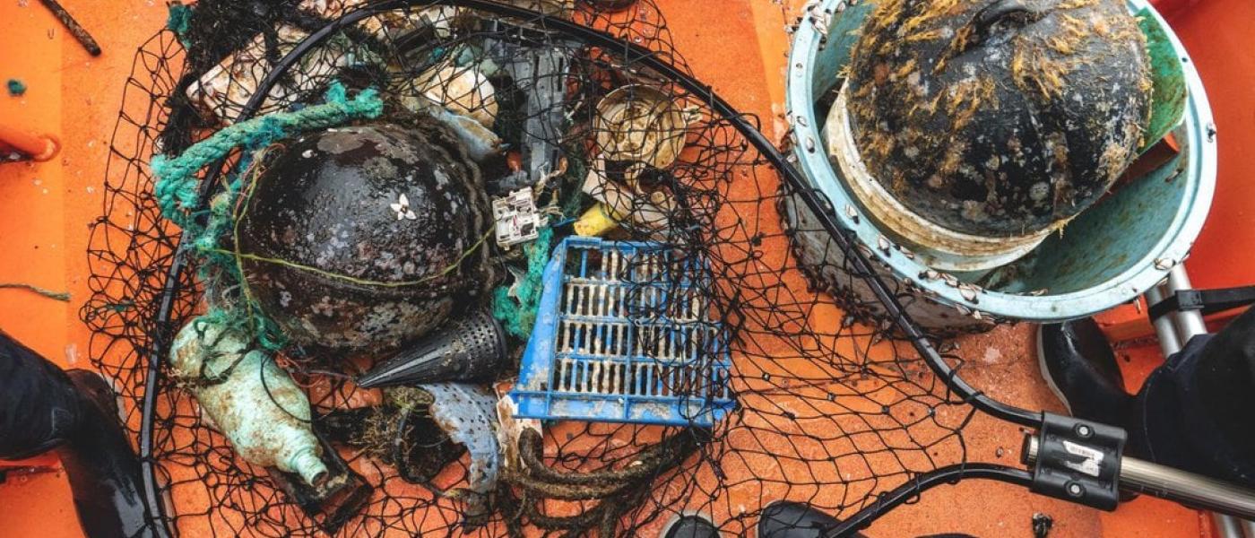 Plastics that contain living organisms on them are gathered in a fishing net on a boat and were collected from the Pacific Ocean