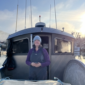 a woman wearing foul weather gear and a winter hat on a boat