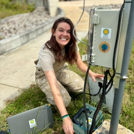 Lydia kneeling beside a logger box