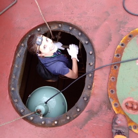 Dr. Flávia Costa Areglado inside a ballast tank before collecting sediments settled on bottom.