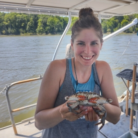 Emily Anderson on a boat holding a blue crab