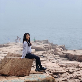 Nina sitting on a granite rock at Acadia National Park in Bar Harbor, Maine